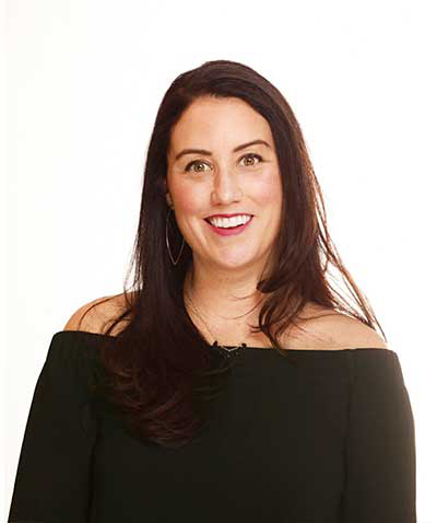 A smiling woman with long dark hair, an event planner at a leading event planning company, wearing a black off-shoulder top against a white background.