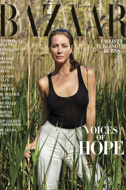 A woman in a black sleeveless top standing amidst tall grass on the cover of Harper's Bazaar magazine, featuring the theme "Voices of Hope," captured at an exclusive event venue space.