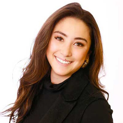 Professional headshot of a smiling woman with long hair, dressed in business attire for an event planning company, against a light background.