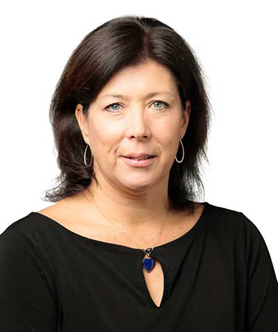 A woman with shoulder-length dark hair wearing a black top and a blue pendant necklace against a white background poses for an event planning company.