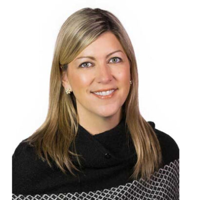 Smiling woman with blond hair, an event planner, wearing a black turtleneck and a checkered scarf.