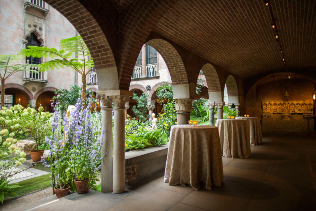 Elegant indoor garden event venue space with arched brick ceilings, decorated tables, and potted plants.