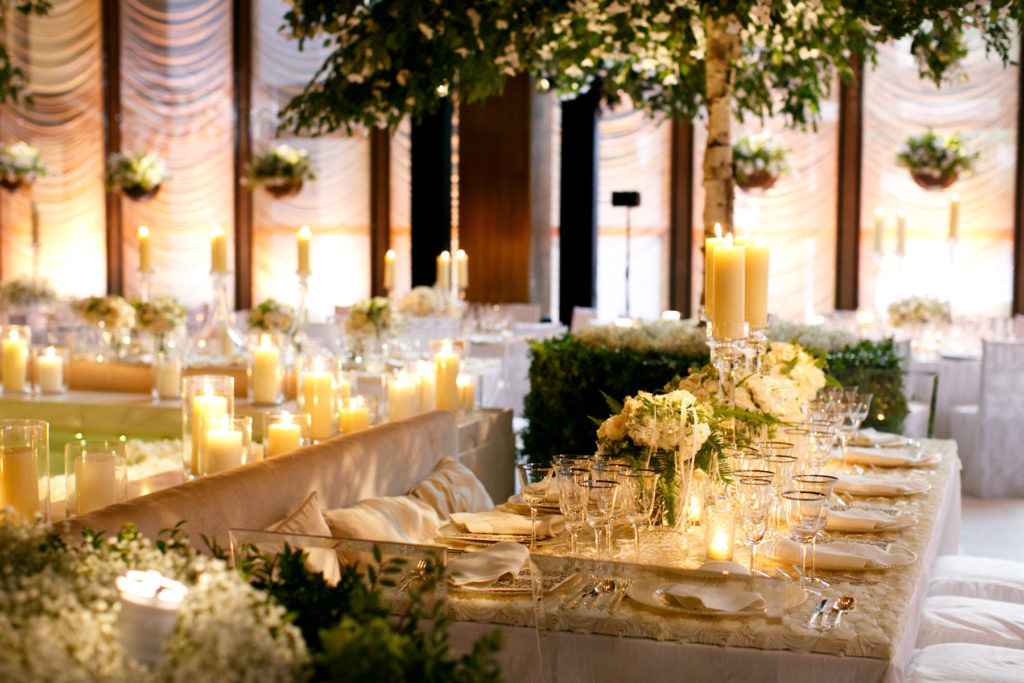 Elegant dining setup by a renowned event planning company for a formal event with candles and floral decorations.