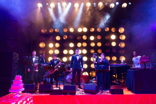 musicians on a stage performing in front of an array of lights.