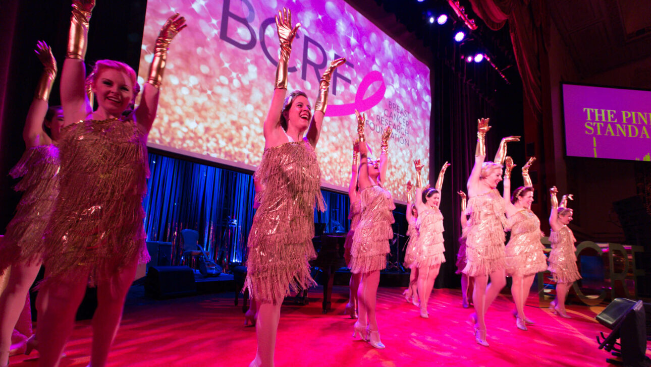 dancers on stage with their hands in the air in front of a screen that says bcrf.