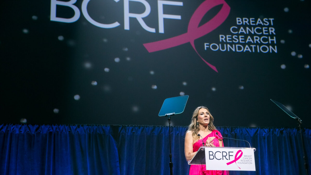 speaker at a podium on stage in front of a screen that says bcrf.