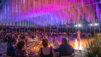 Elegant evening event planned by professional event planners with guests seated at tables under a canopy of colorful streamers.