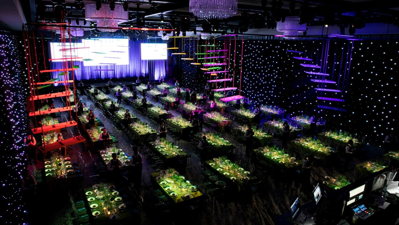dark room with many tables and neon stairs hanging in the air.