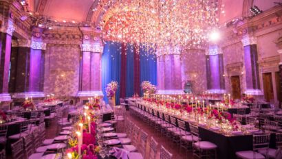 Elegant gala event setup with ornate tables, floral centerpieces, and a dramatic ceiling light installation in a grand hall by a top-tier event planning company.