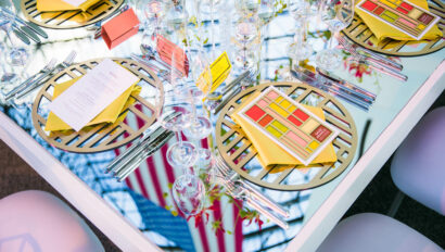 Elegant table setting with geometric placemats, fine glassware, and folded menus at a formal event venue space.