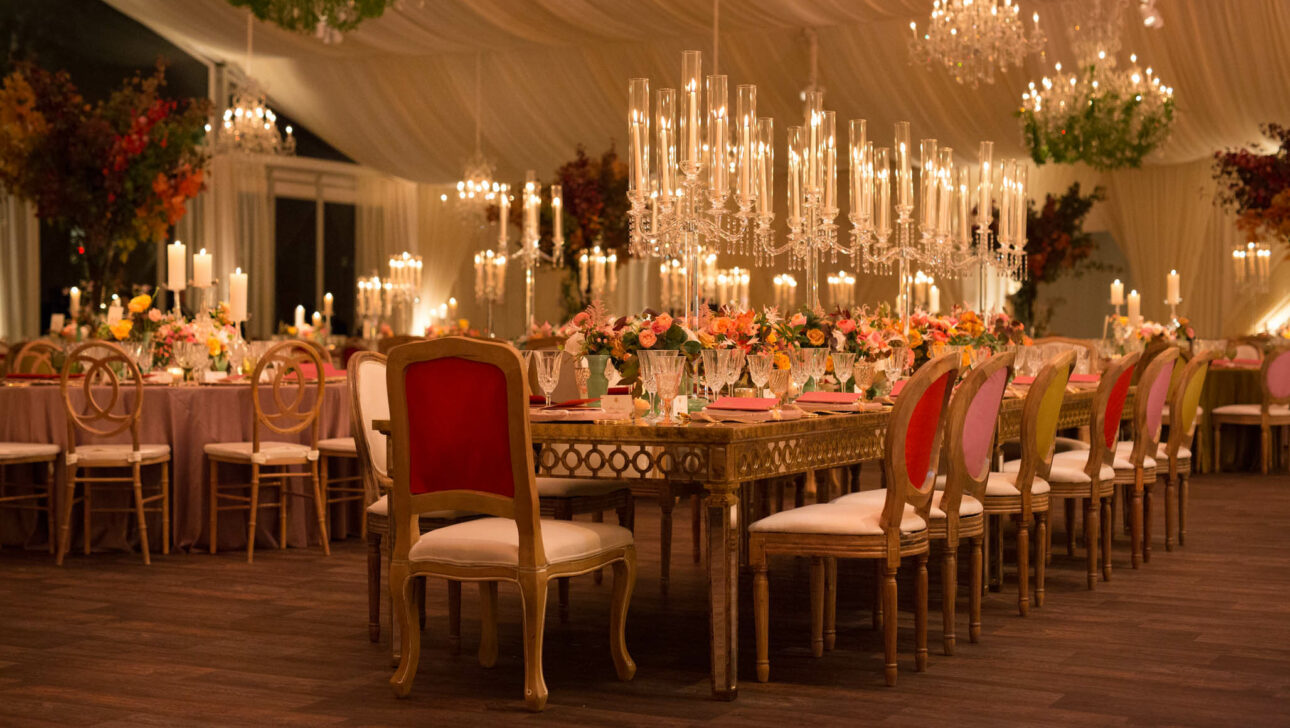 Elegant event venue space decorated with chandeliers, candles, and floral arrangements for a formal event.