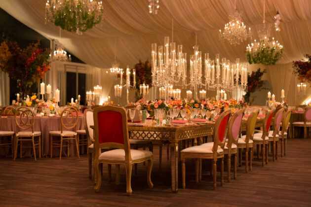 Elegant event venue space decorated with chandeliers, candles, and floral arrangements for a formal event.