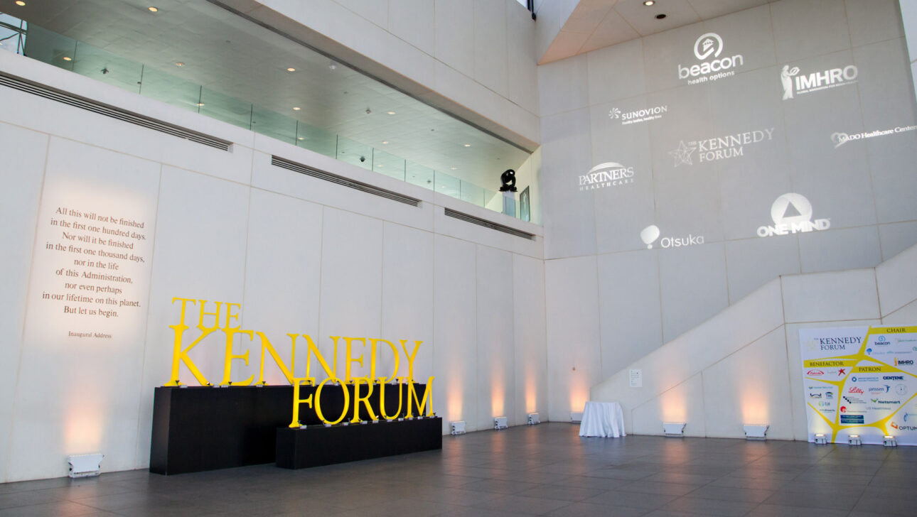 large lobby with company logos on a wall and a large sign that says kennedy forum.