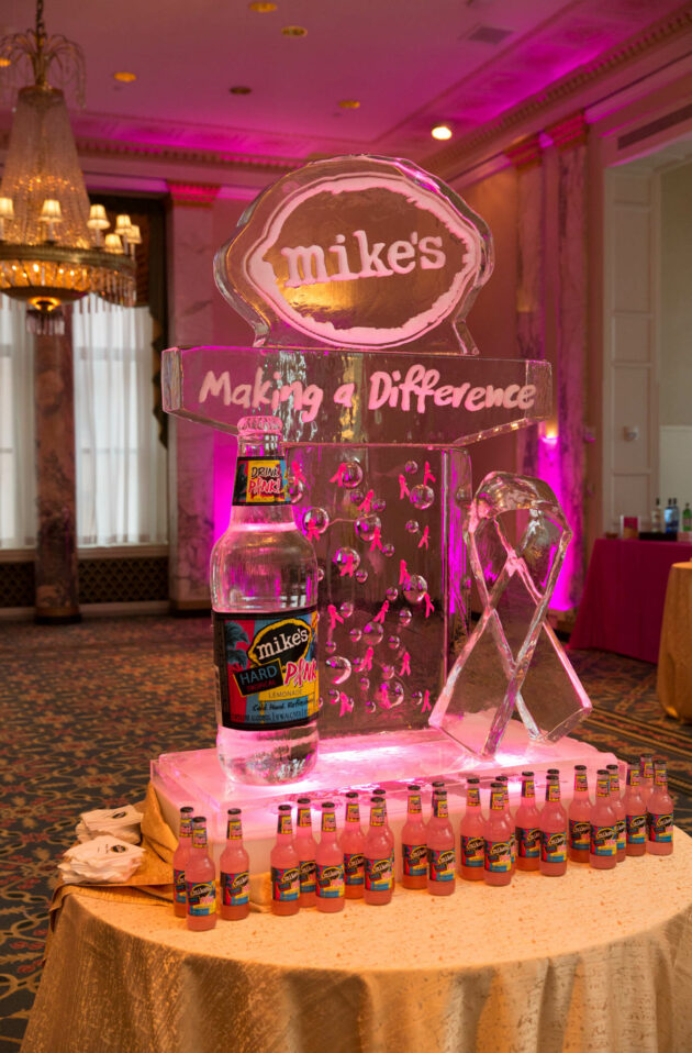 Display featuring mike's hard lemonade bottles, a tiered ice sculpture with brand signage, and ribbon decorations curated by an event planning company.