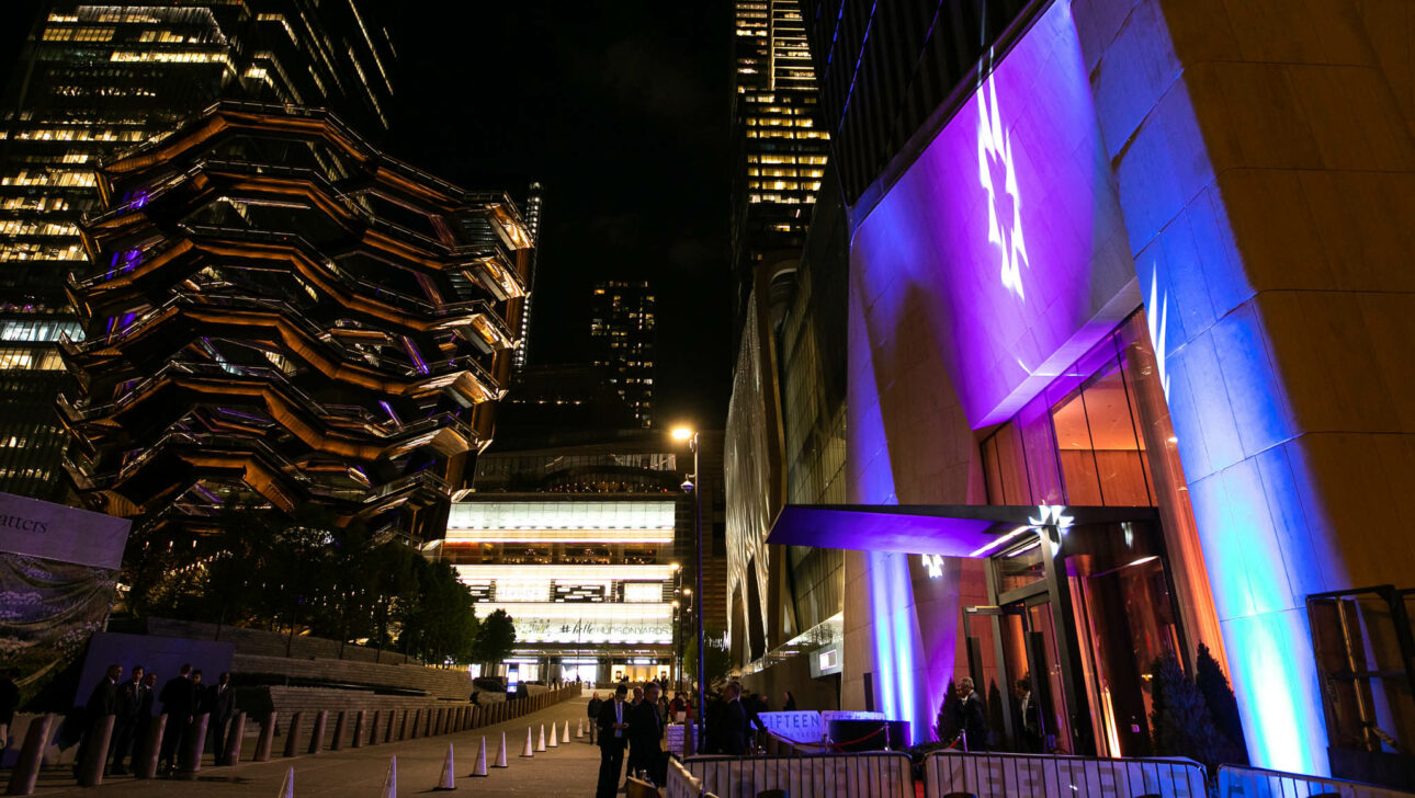 Evening view of a contemporary event venue space with illuminated architectural structures in an urban plaza.