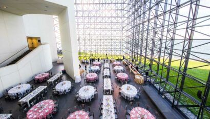 Banquet setup in a modern hall with large glass windows and geometric metal framework, designed by top event planners.