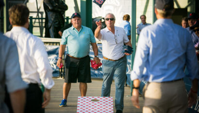 men playing cornhole with red sox bean bag.