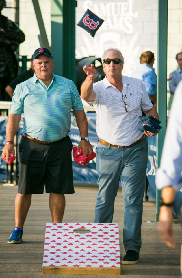 men playing cornhole with red sox bean bag.