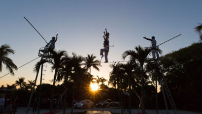 tightrope walkers performing outside in front of the sunset.