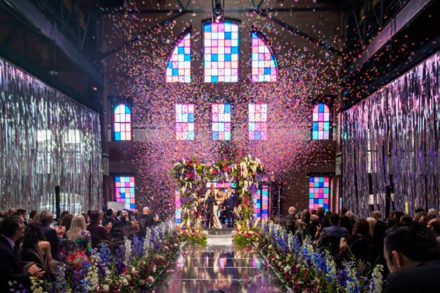 bride and groom kissing at the altar with confetti falling around them.