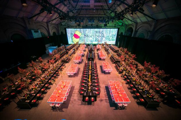 Elegant gala dinner setting with decorated tables arranged for the 2016 storybook ball, organized by a top event planning company, in a grand hall.