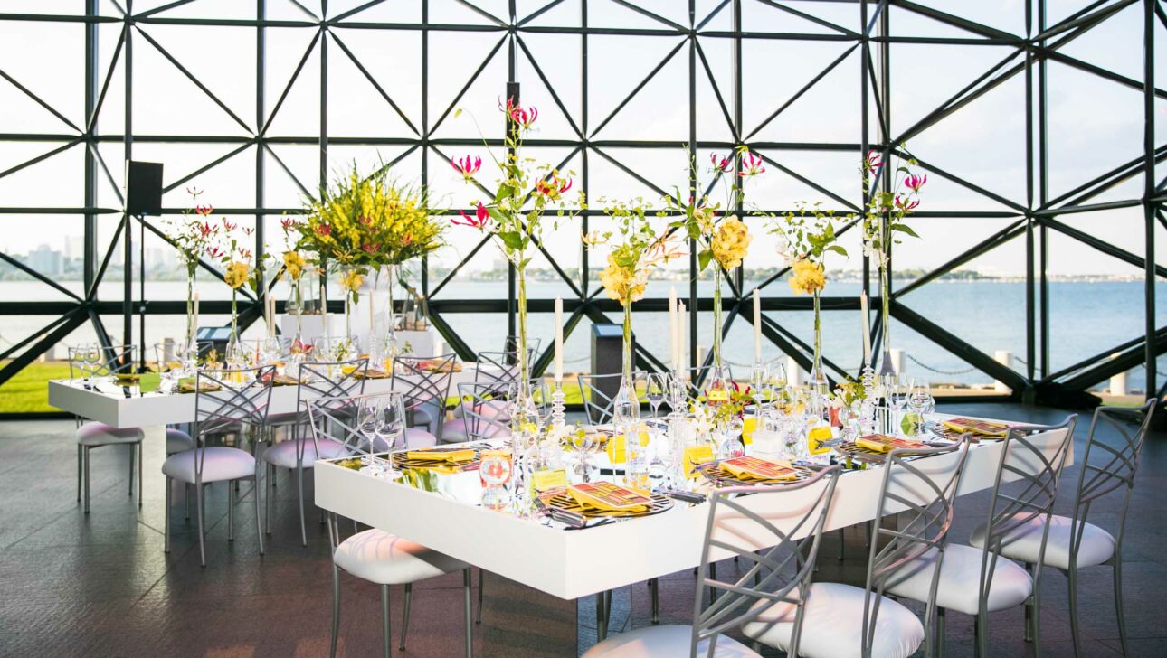 decorated dining table in a large glass room looking out to the water.