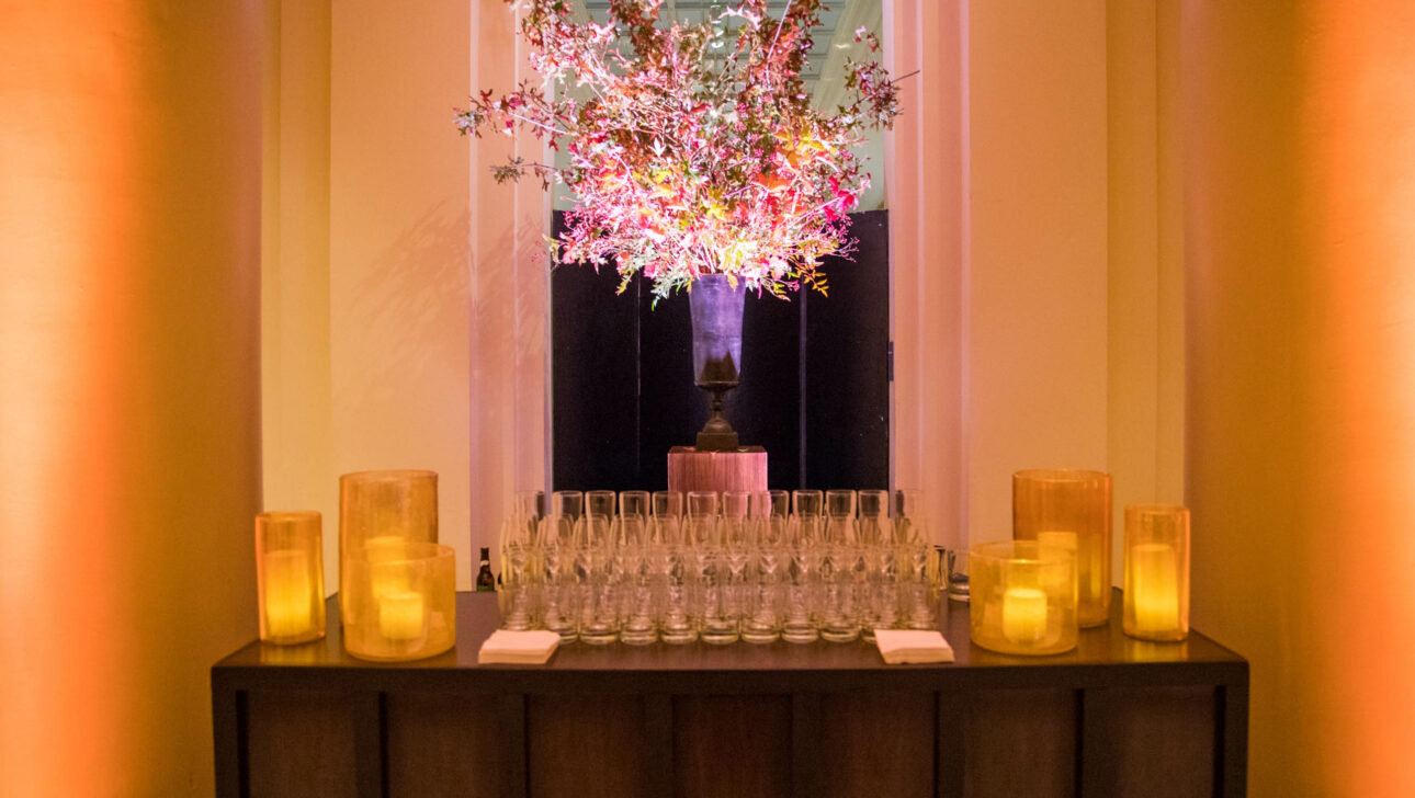 glassware set on a table in front of a flower arrangement.