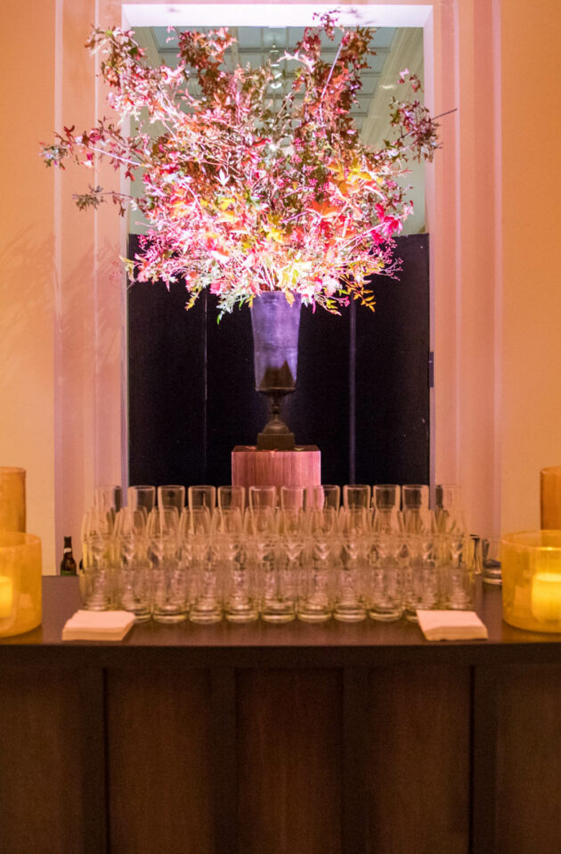 glassware set on a table in front of a flower arrangement.
