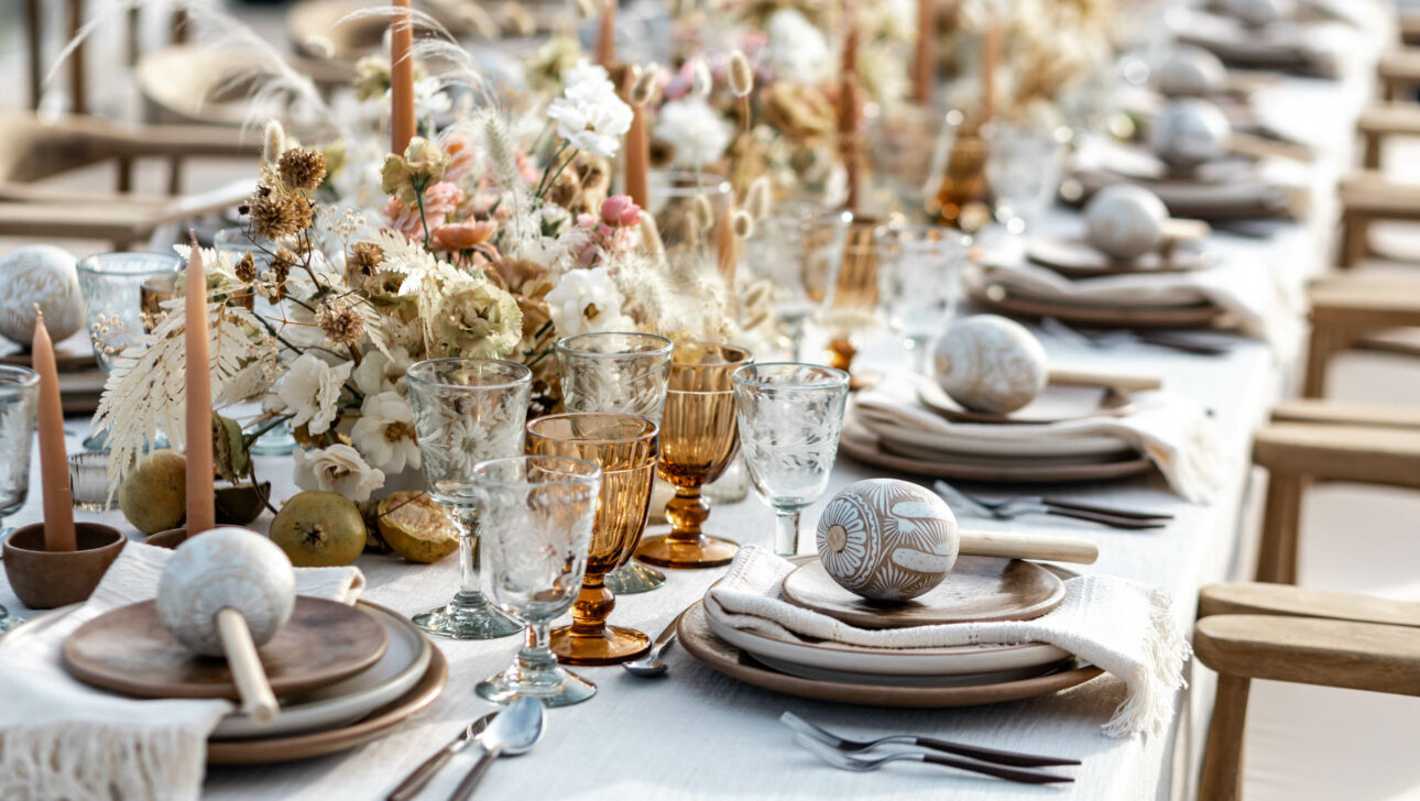 Elegant outdoor dining setup with natural-themed table decorations and place settings, organized by a top event planning company.