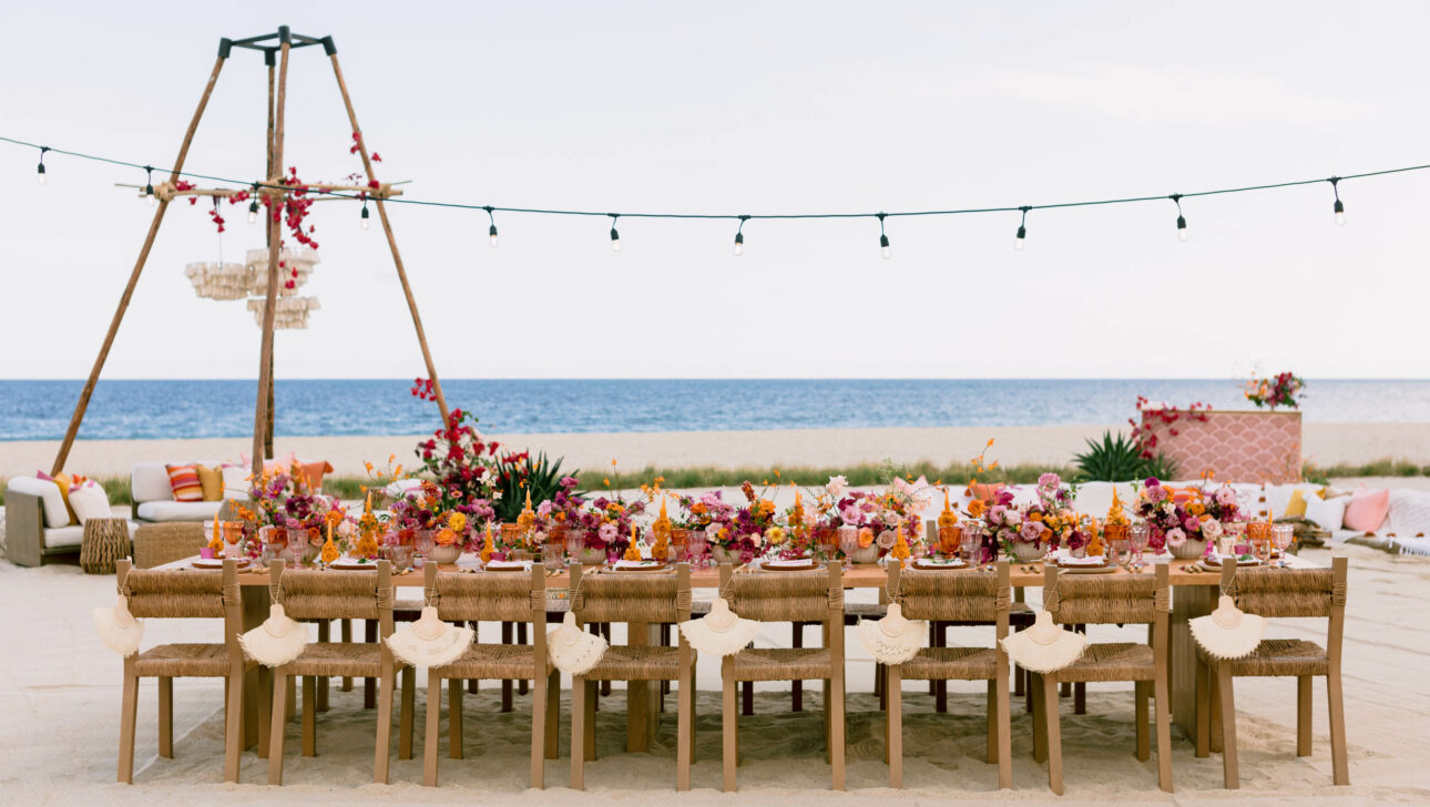 decorated dining table set for a wedding on a beach.