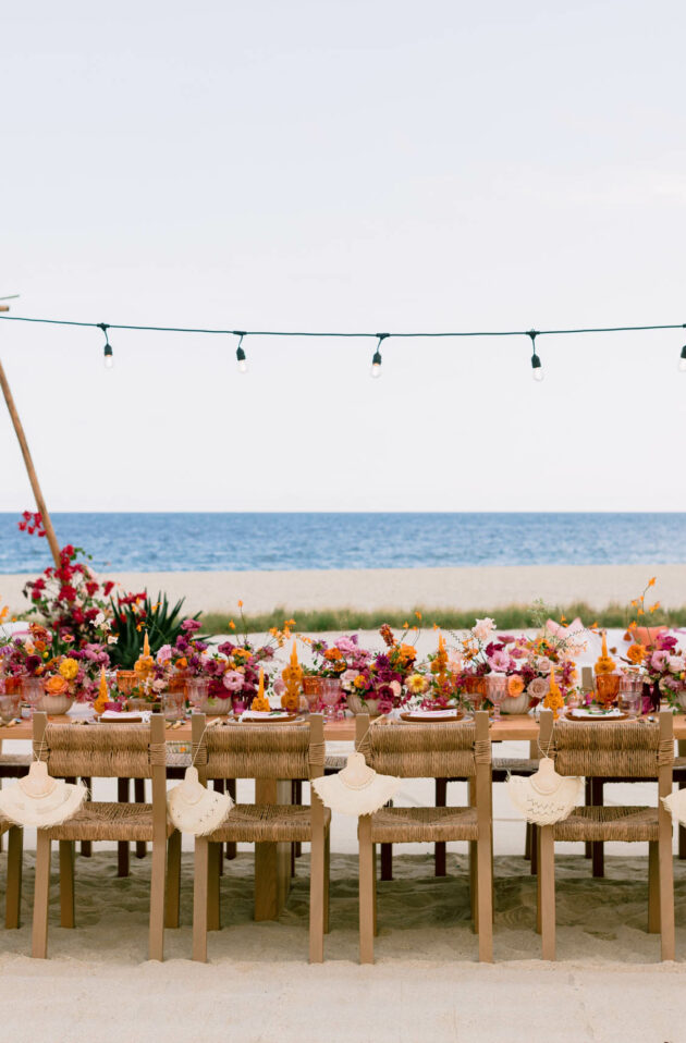 decorated dining table set for a wedding on a beach.