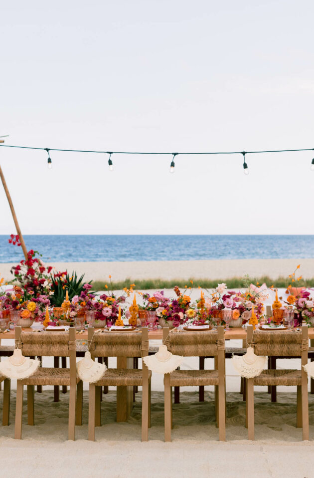 Outdoor dining setup by the sea with a decorated table and string lights, meticulously arranged by an event planning company.