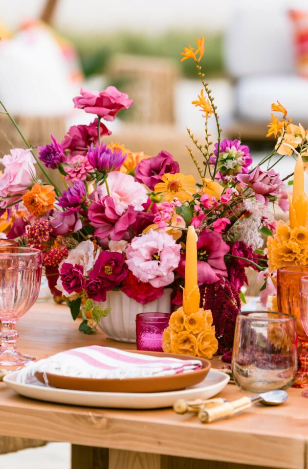 A vibrant outdoor table setting with colorful floral arrangements and pink glassware, perfectly curated by a leading event planning company.