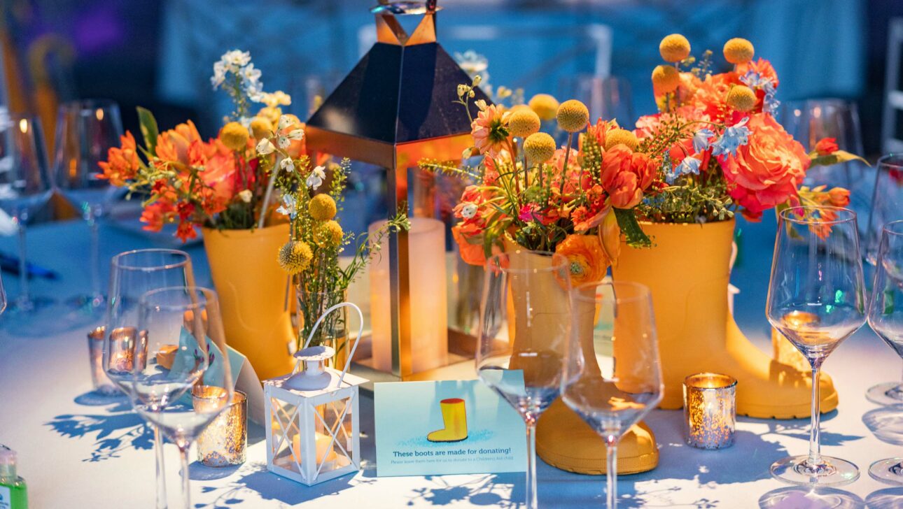 Colorful table setting with floral arrangements and elegant dinnerware at an event venue space.