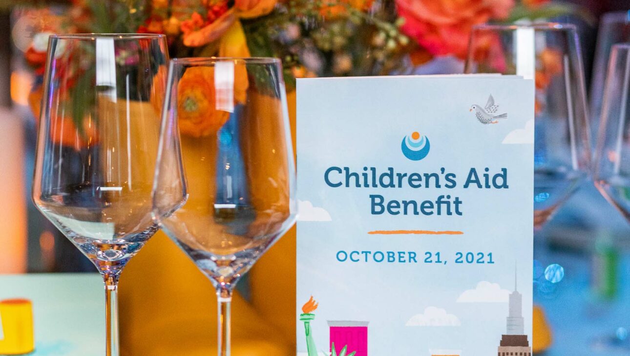 Elegant table setting with promotional material for a children's aid benefit event, organized by an event planning company, held on October 21, 2021.