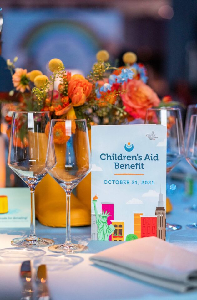 Elegant table setting with promotional material for a children's aid benefit event, organized by an event planning company, held on October 21, 2021.