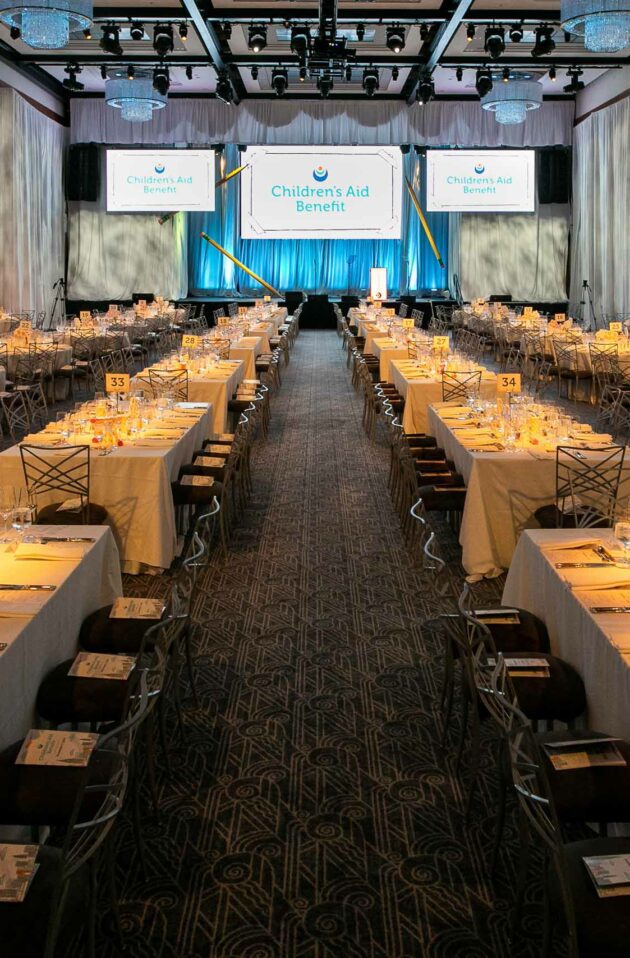 decorated reception hall with a sign on stage that says childrens aid benefit.