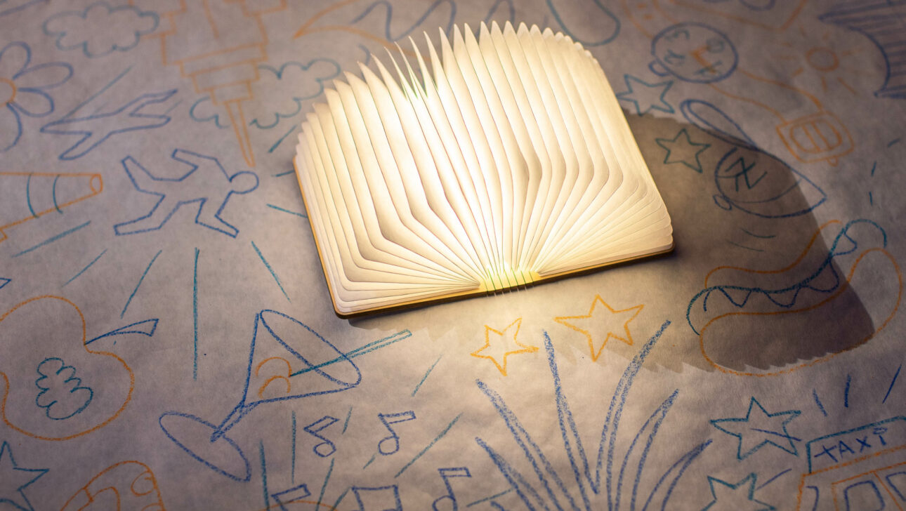 An open book with pages fanned out on a surface with doodles related to event planning.