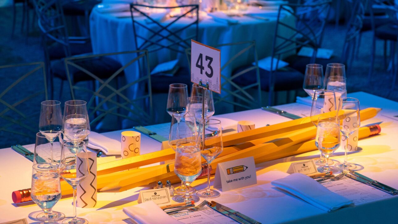 Elegant banquet table set for an event by a professional event planning company, with a numbered centerpiece and soft blue lighting.