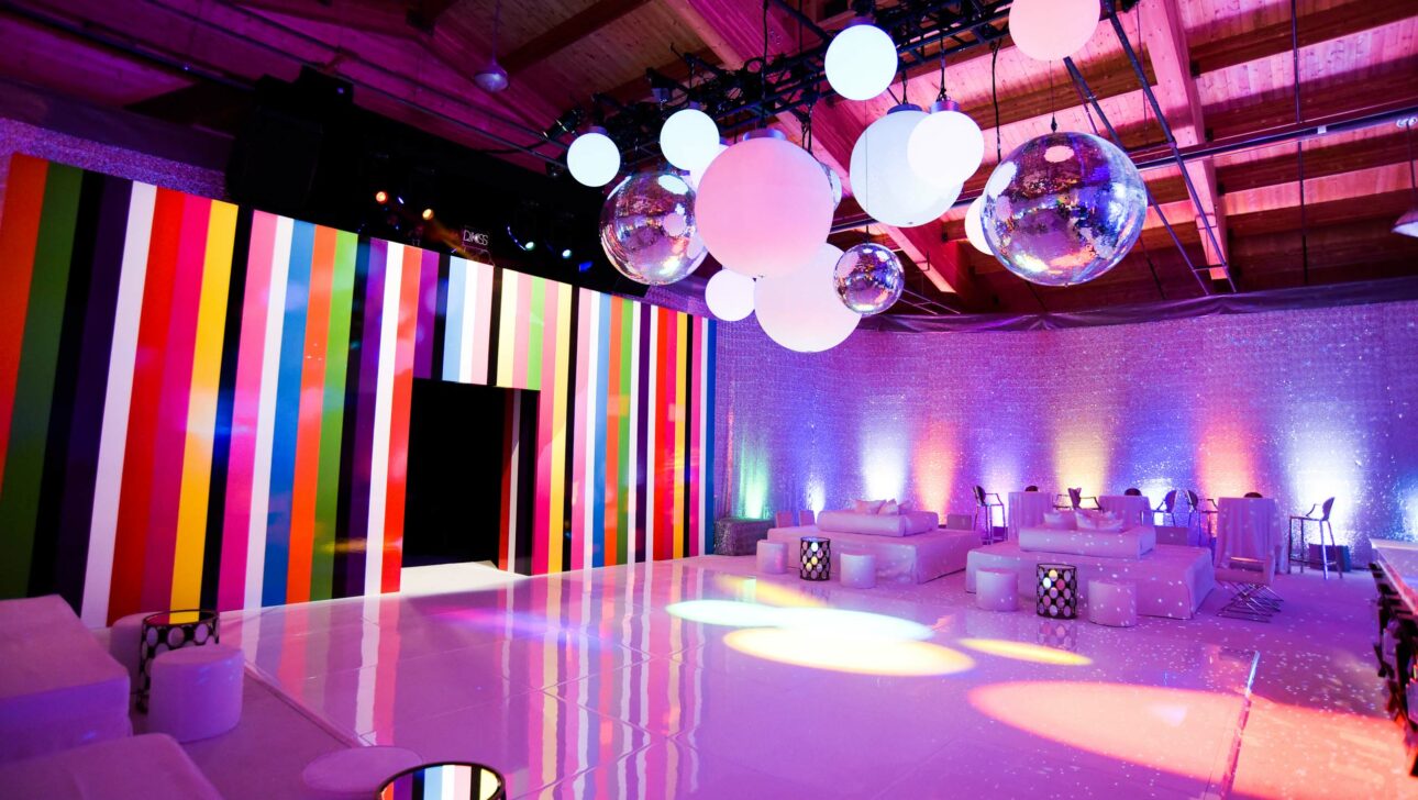 purple hued lounge room with a rainbow striped wall and large balls suspended from the ceiling.