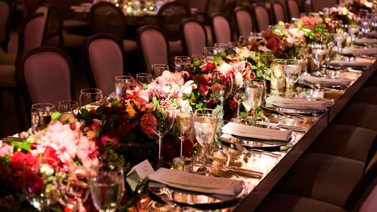 Elegant banquet table setting with floral centerpieces and glassware for a formal event, meticulously arranged by a leading event planning company.