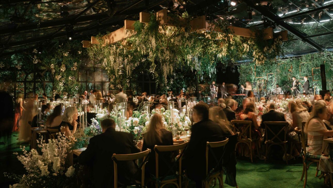 elaborate dining room decorated with flowers in a greenhouse at night.