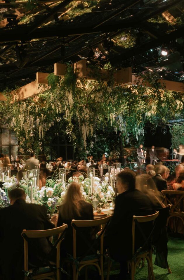 elaborate dining room decorated with flowers in a greenhouse at night.