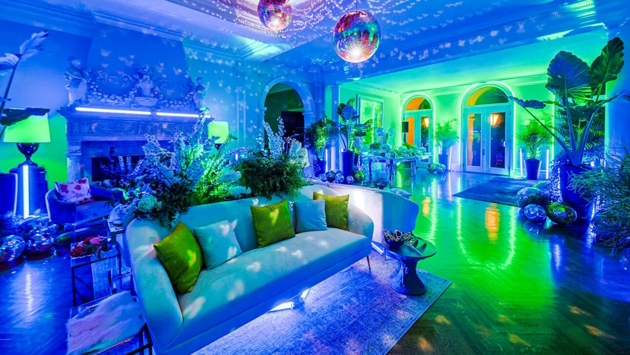 A vibrant blue-hued event venue space with disco balls, illuminated decor, and plush seating arranged for an event.