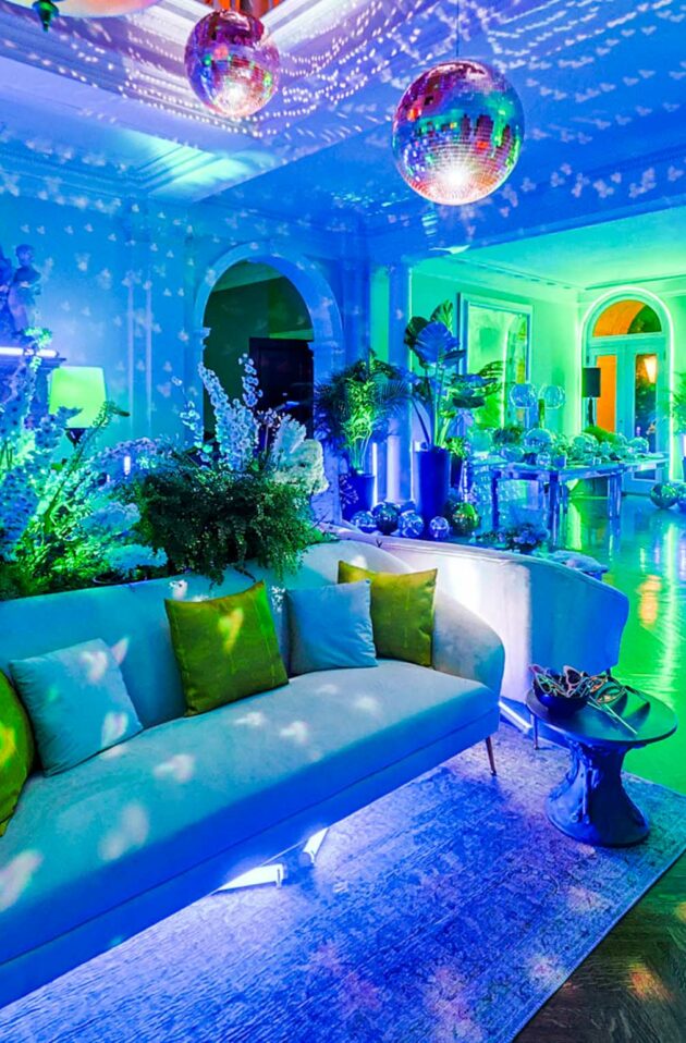 A vibrant blue-hued event venue space with disco balls, illuminated decor, and plush seating arranged for an event.