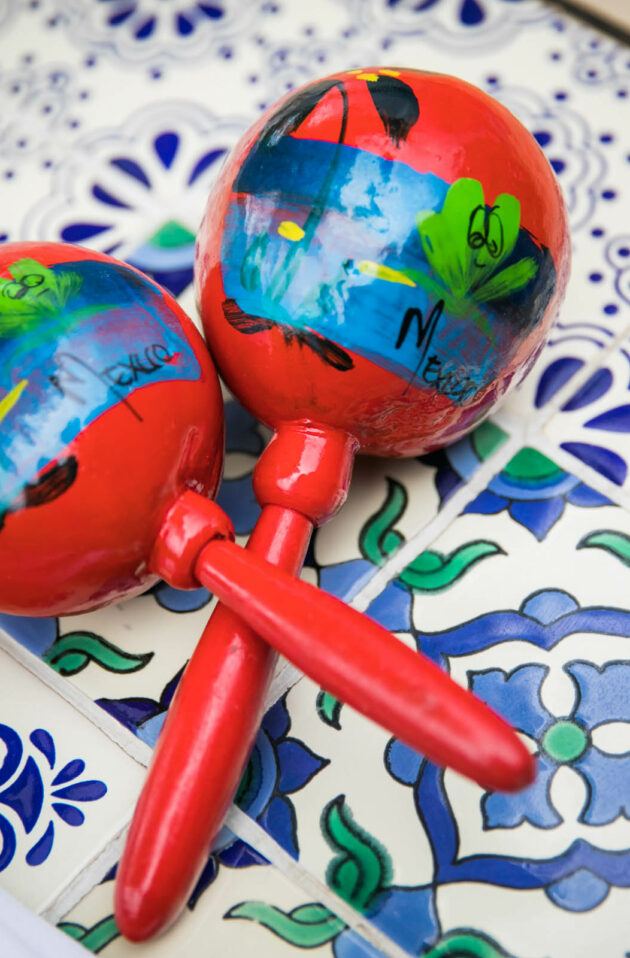 Two colorful maracas resting on a patterned tile surface at an event venue.