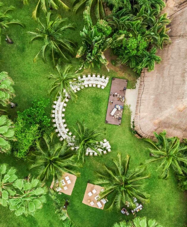 c shaped dining table under palm trees.