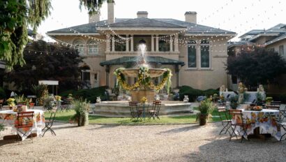 fountain surrounded by tables in front of an estate house.