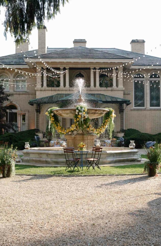 fountain surrounded by tables in front of an estate house.
