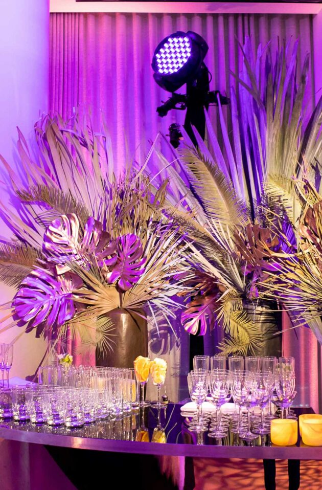 glasses on a bar in front of tropical decorations on a high floor of a building in new york city